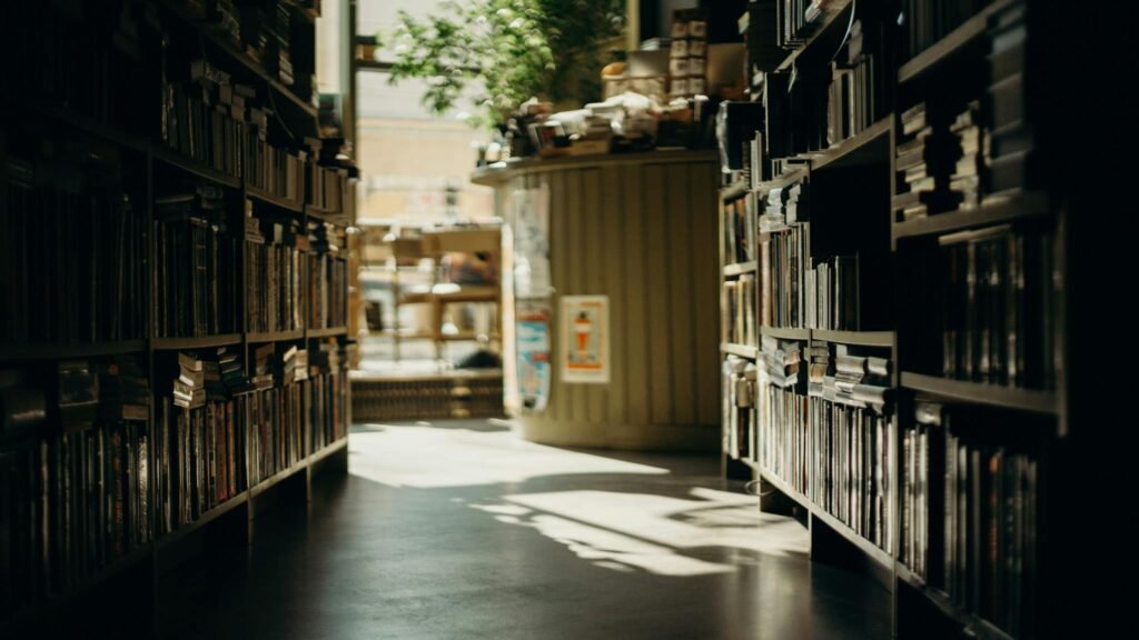 A sunlit aisle in a cozy bookstore with lined bookshelves, creating a warm and inviting atmosphere.