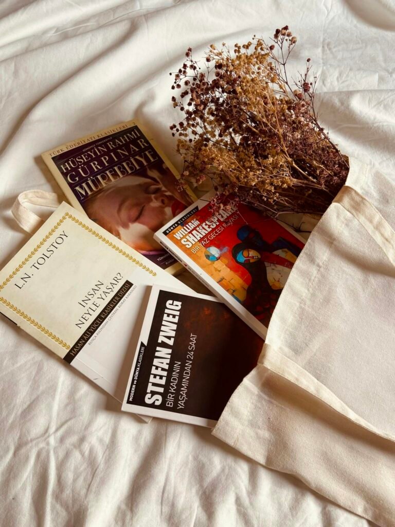 Aesthetic display of books and dried flowers overflowing from a cotton bag.